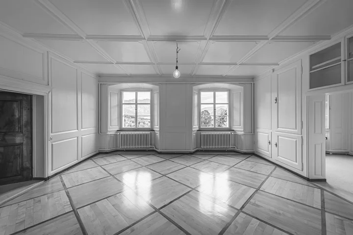 An empty room with bare floorboards after the clearance