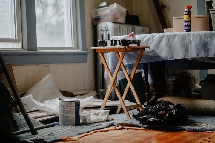 A room part-way through a clearance, dust sheets down and the contents stacked